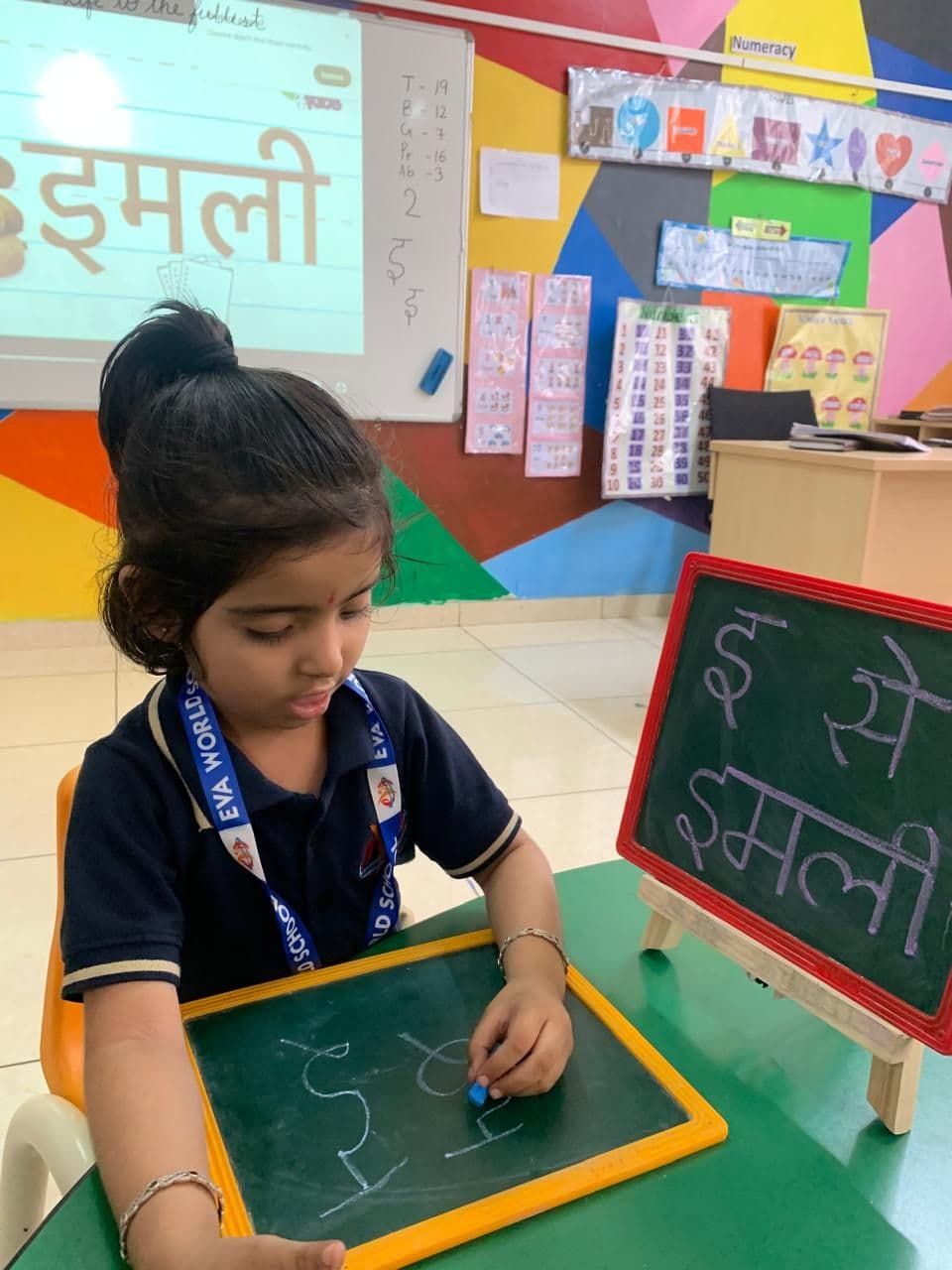 A girl writing on a small slate at her desk