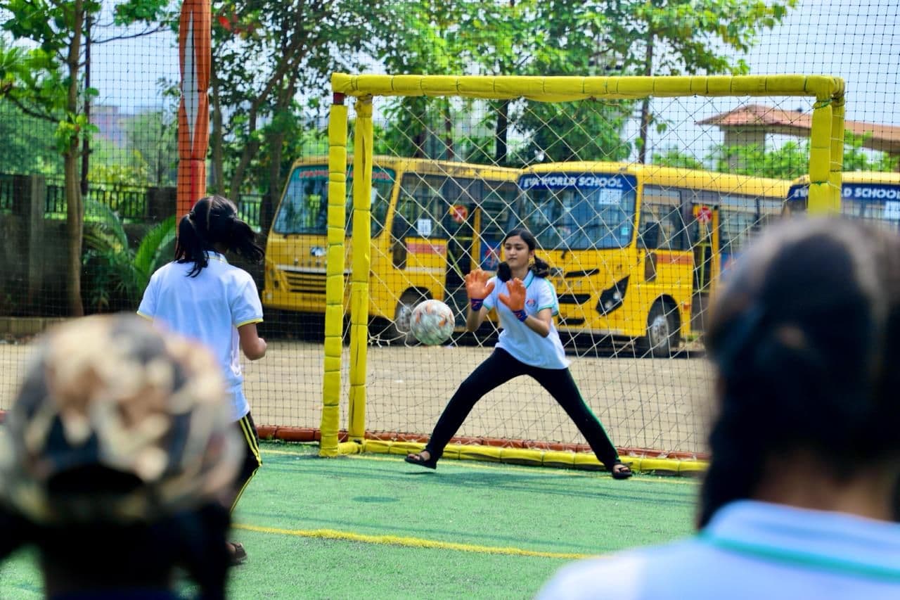 A student goalkeeper watching play on a small football pitch