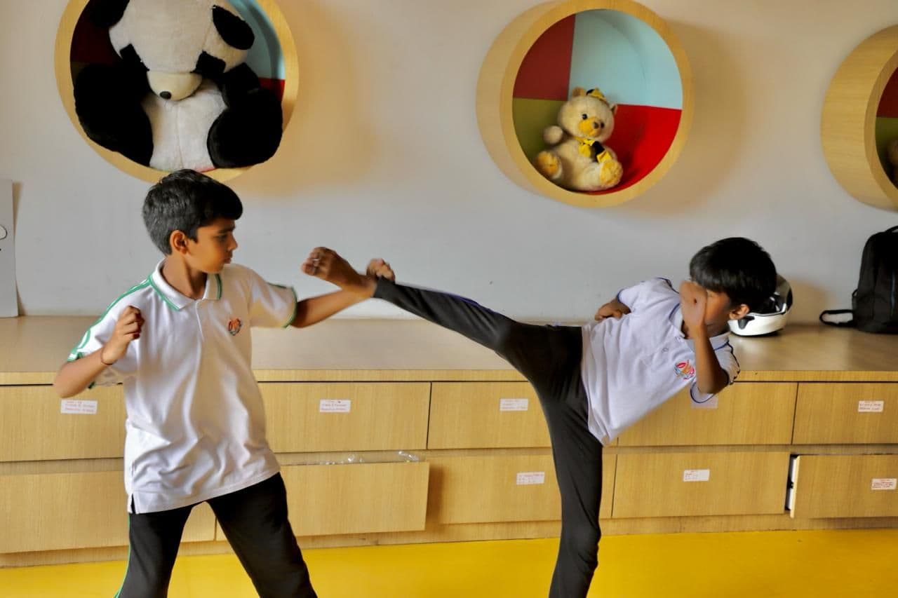 Two students practising martial arts kicks in an activity room
