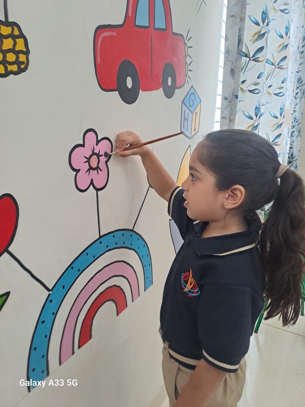 A girl painting a flower on a decorated classroom wall