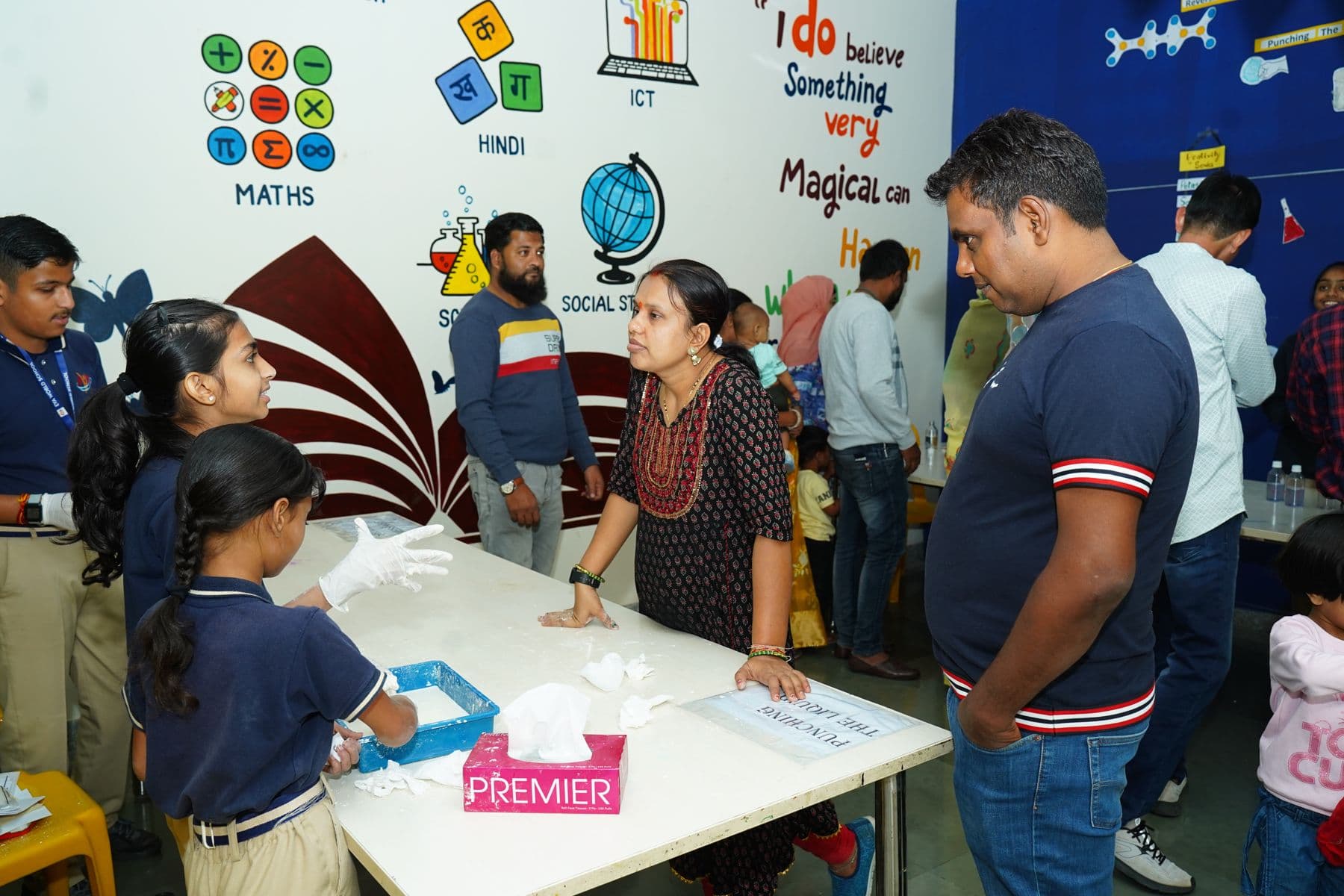 Parents speaking with teachers at a classroom subject display